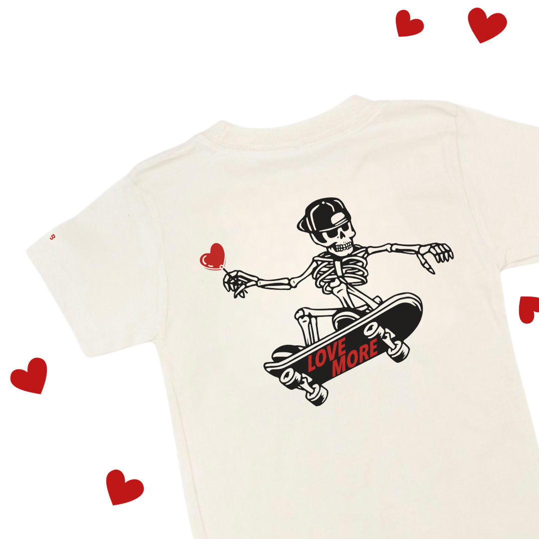 natural colored child shirt with the Love More graphic design printed on the back
