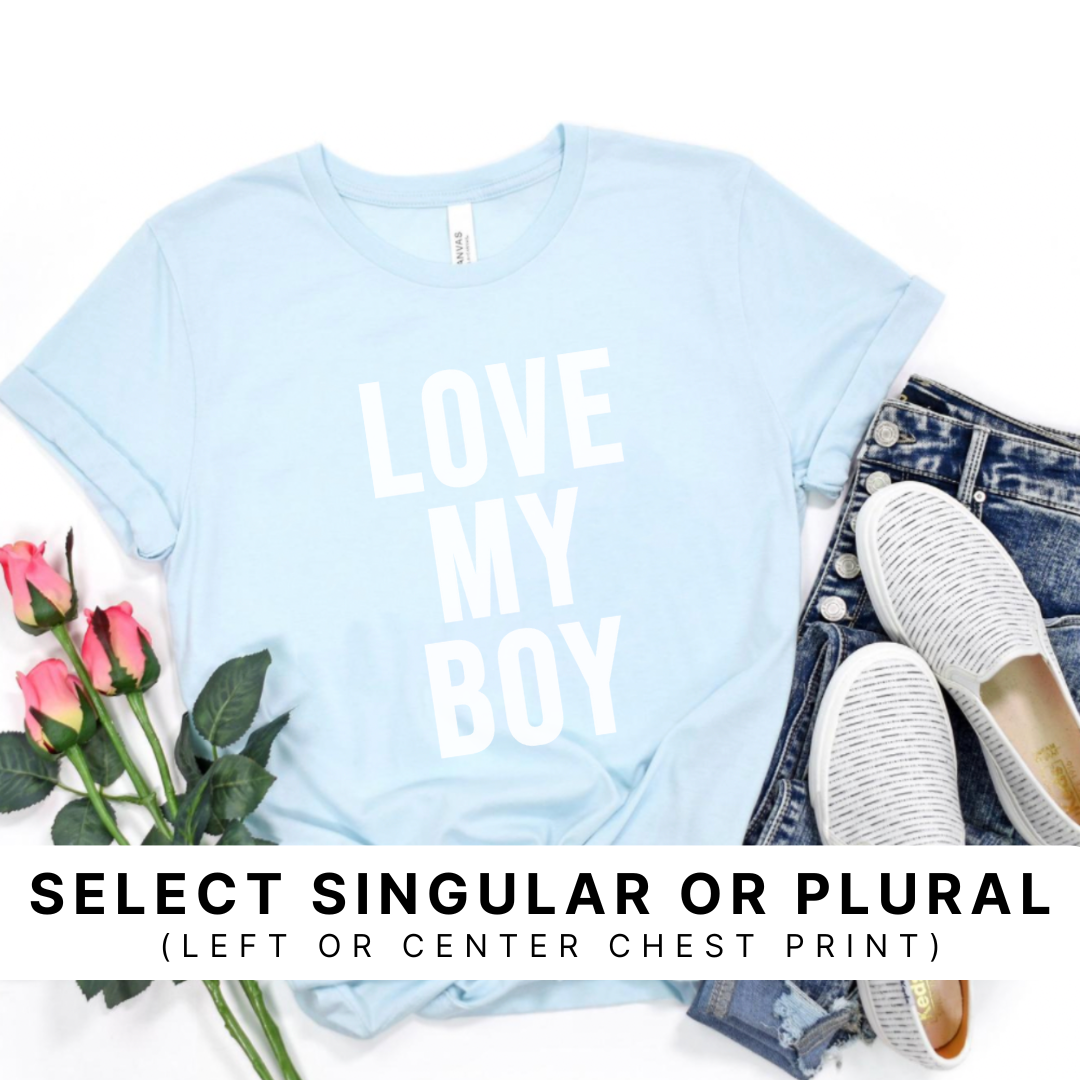 Styled flat lay of an ice blue graphic tee featuring white ink text that reads “Love My Boy.