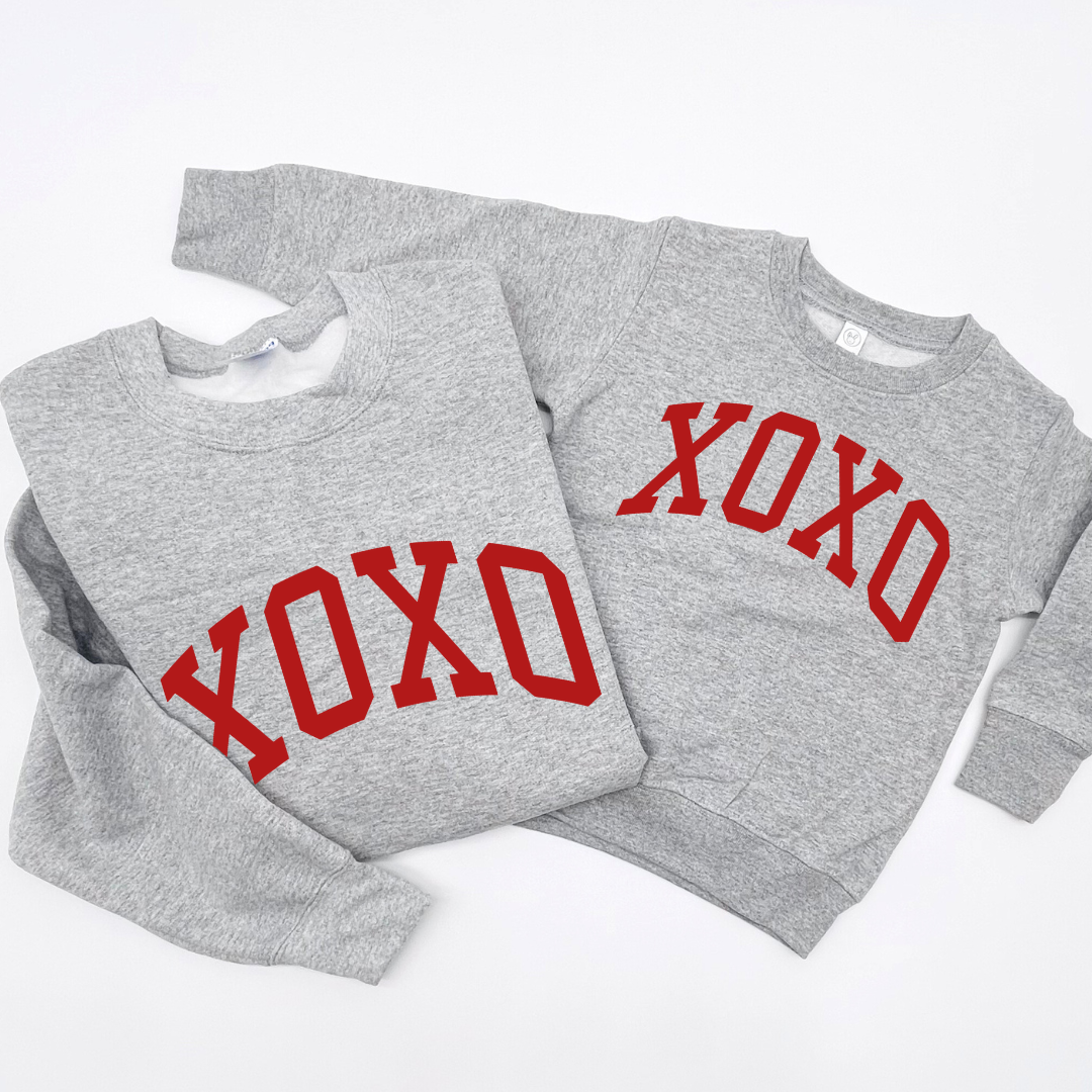 adult and kids fleece heather light gray fleece pullover laying side by side with the XOXO graphic design