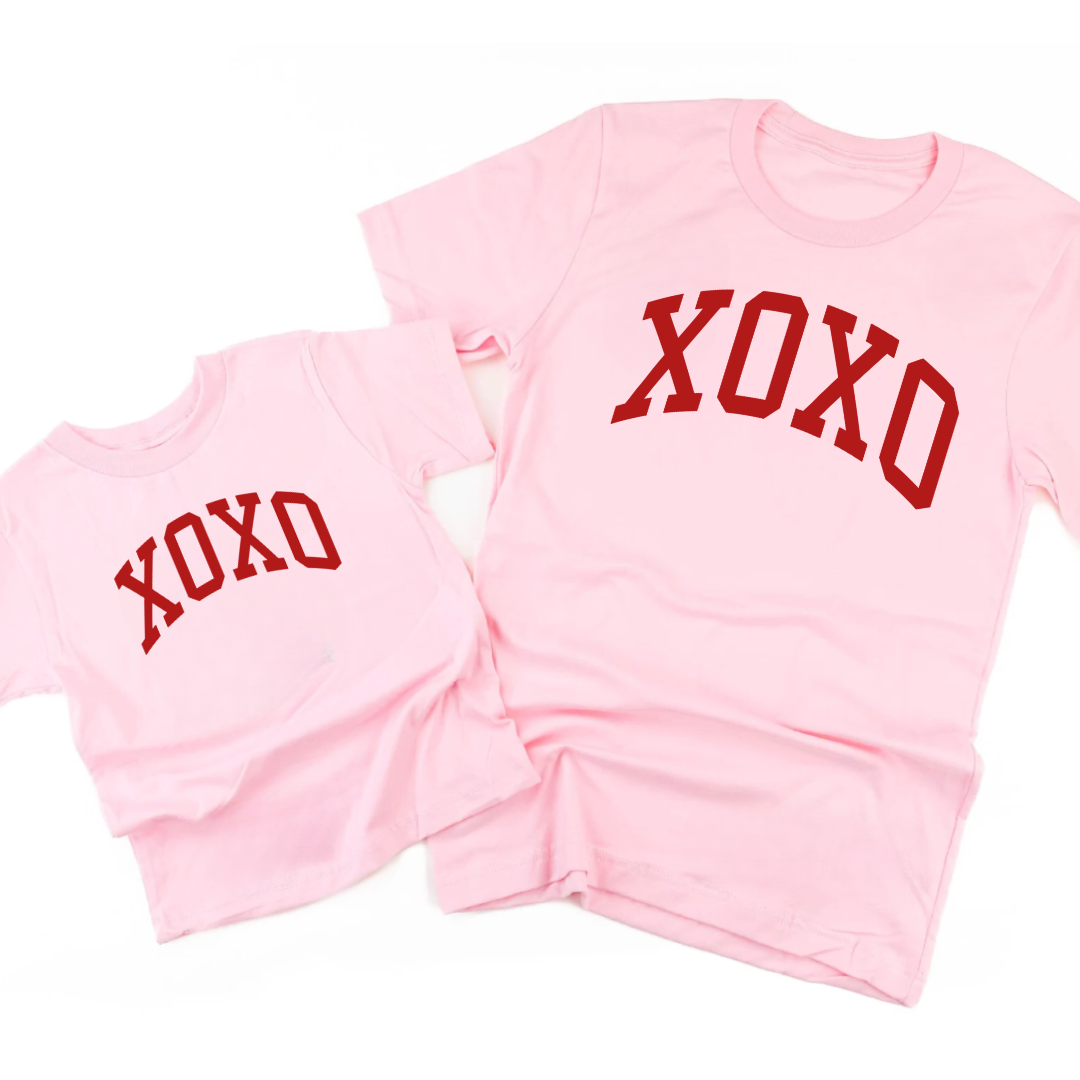 side by side adult and kids pink tees with the bold XOXO graphic design on each printed in red ink
