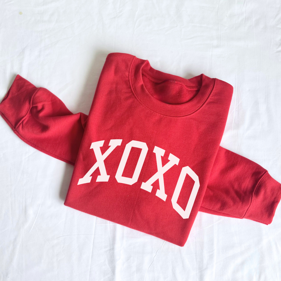red fleece pullover folded with XOXO graphic design in white ink