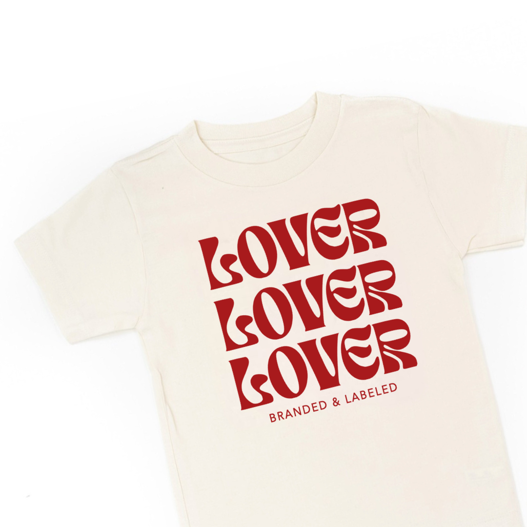 Kids natural color tee featuring the “Lover on Repeat” graphic design printed on the front.