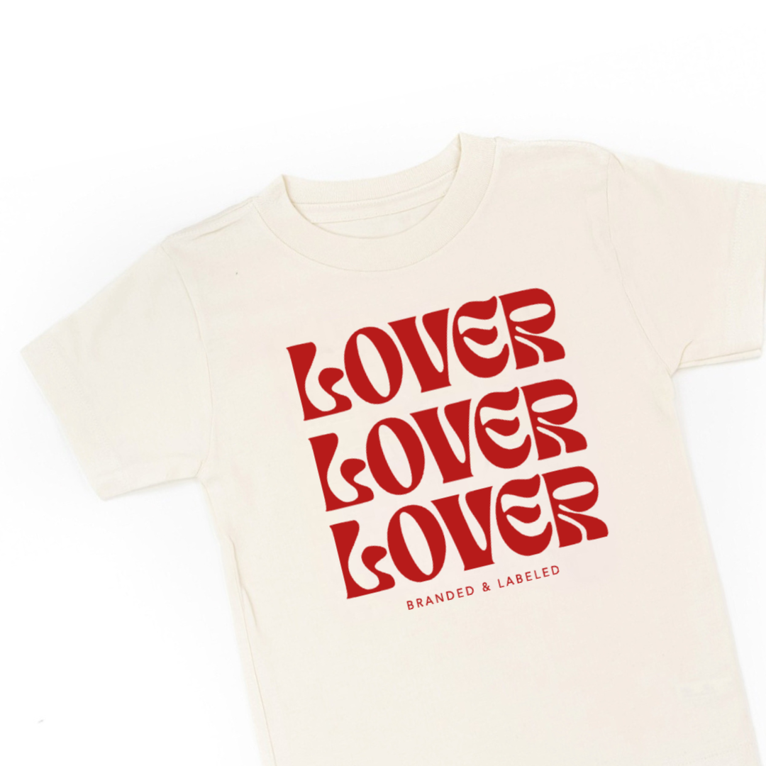 Kids natural color tee featuring the “Lover on Repeat” graphic design printed on the front.
