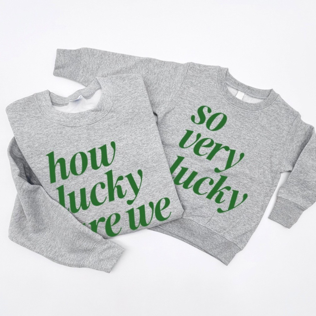 matching set of 2 heather light gray fleece pullovers - one adult with How Lucky Are We" and one kids with "So Very Lucky" printed on the front