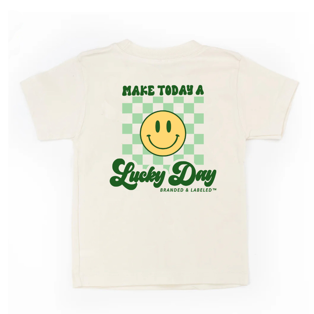 Flat lay kids natural. colored short sleeve tee with the "Make today a Lucky day" graphic design