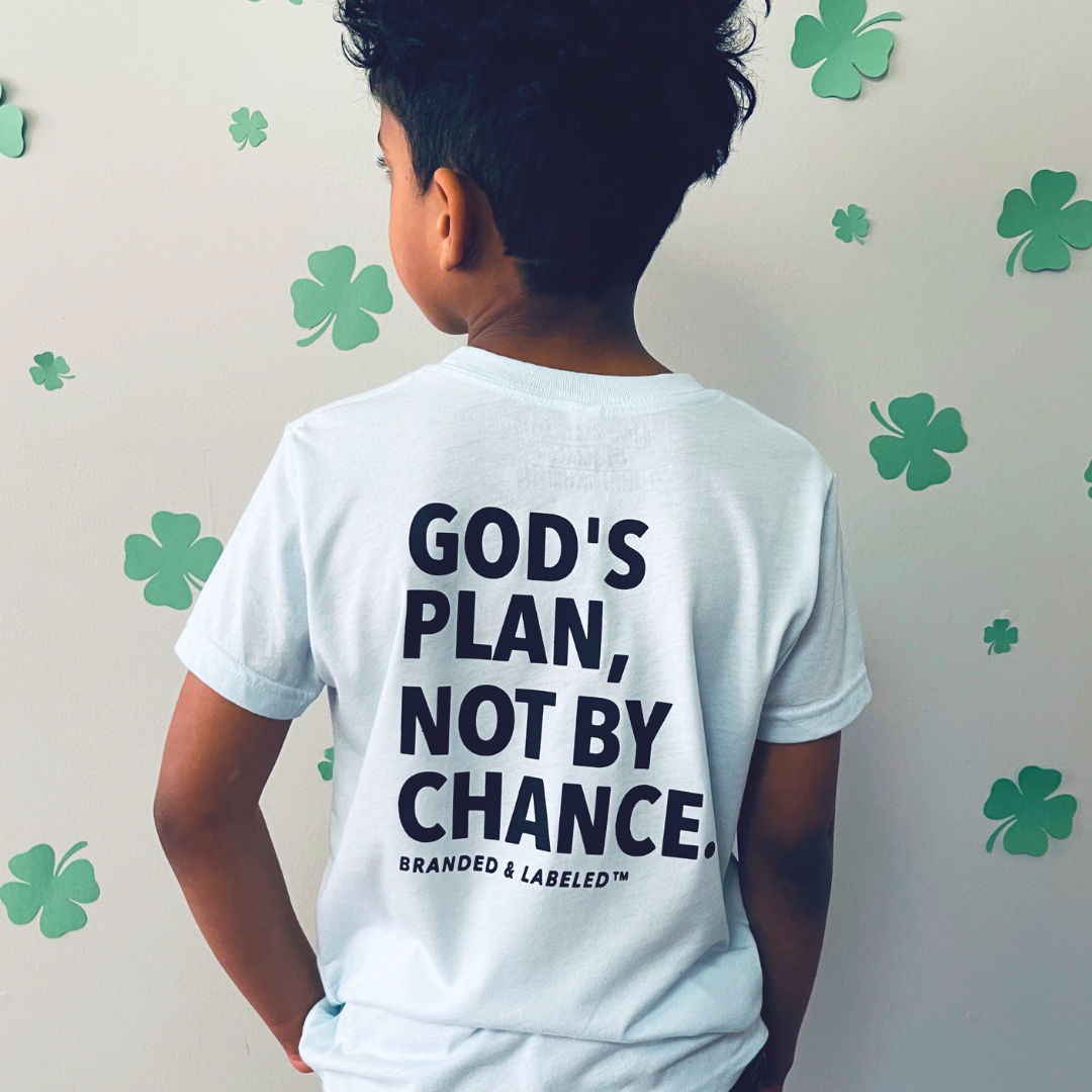 Young boy shown from behind modeling an ice blue tee with a design that reads "God's plan, not by chance" with "Branded & Labeled™" printed underneath