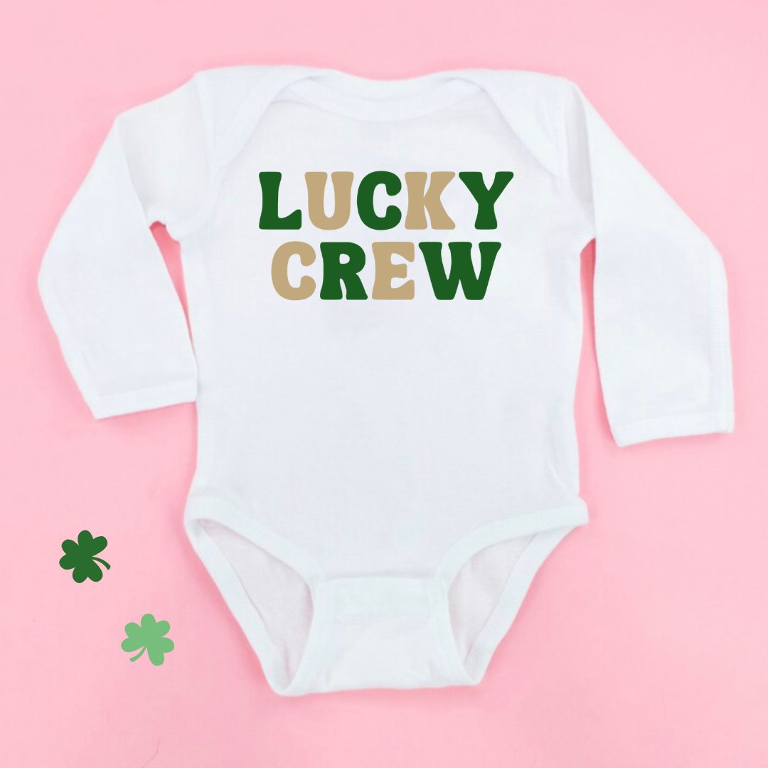 flat lay of an infant long sleeve bodysuit in white with "Lucky Crew" printed in a bold font that alternates in colors between gold and green
