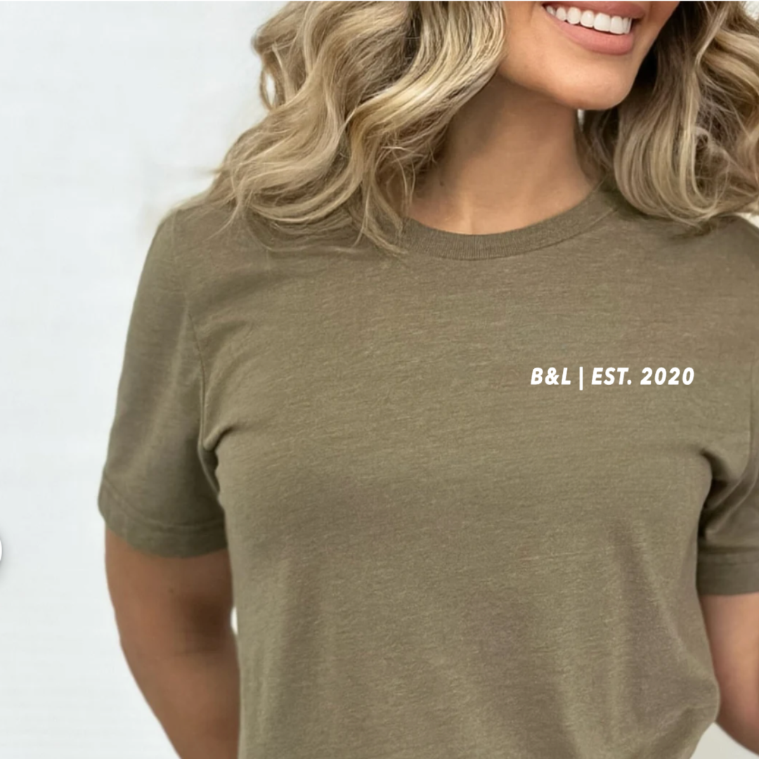 woman modeling a olive short sleeve shirt with a left chest print that says "B&L| EST. 2020"