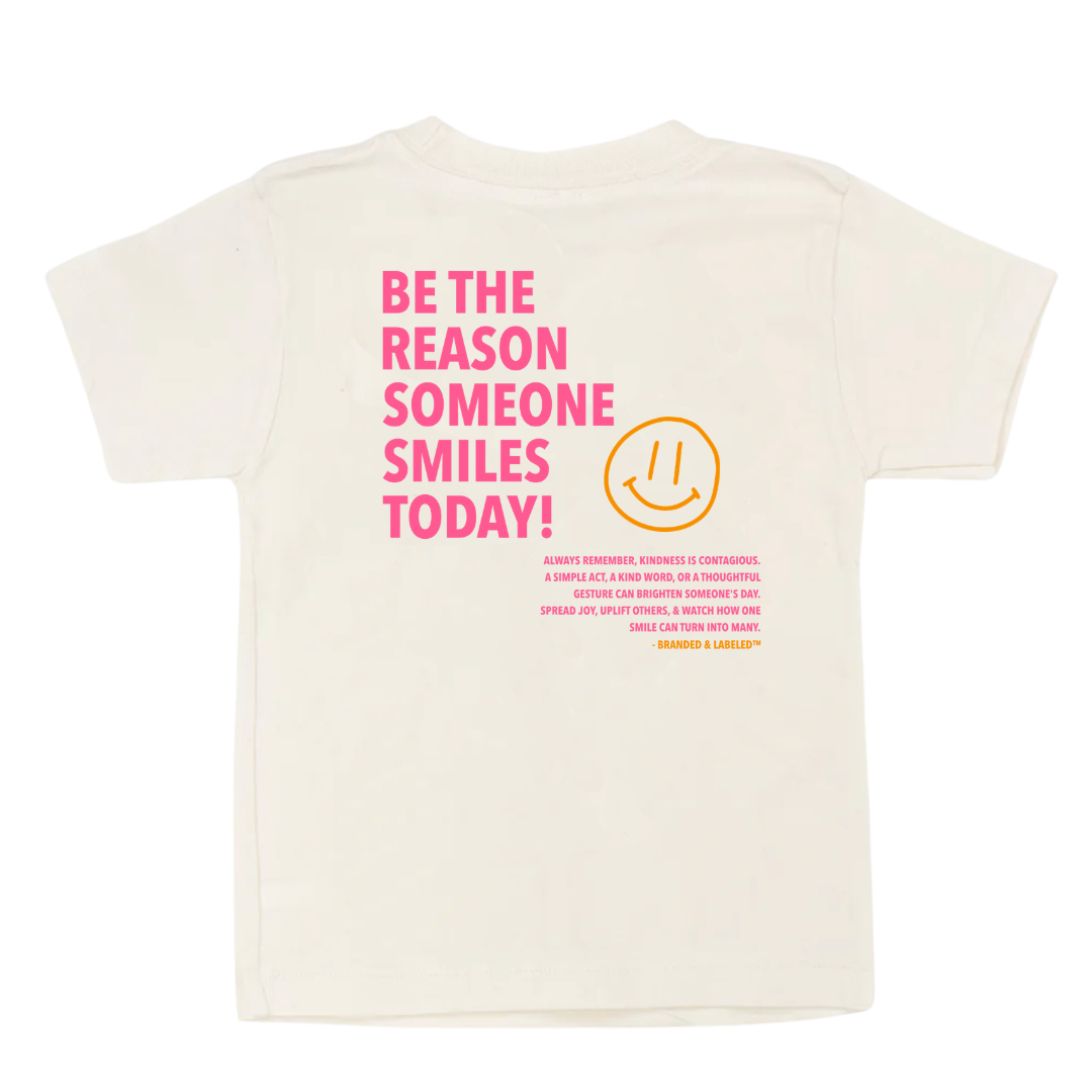 Back of kids graphic tee featuring the phrase “Be the Reason Someone Smiles Today” with an inspirational kindness message and subtle Branded & Labeled text underneath.