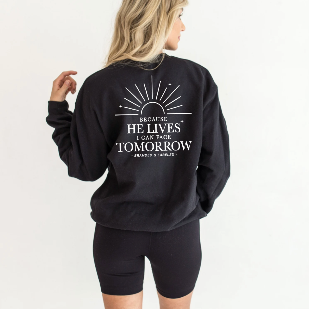Woman wearing a fleece pullover showing the back design that reads “Because He Lives I Can Face Tomorrow” with small “Redeemed” text printed on the front from Branded & Labeled.