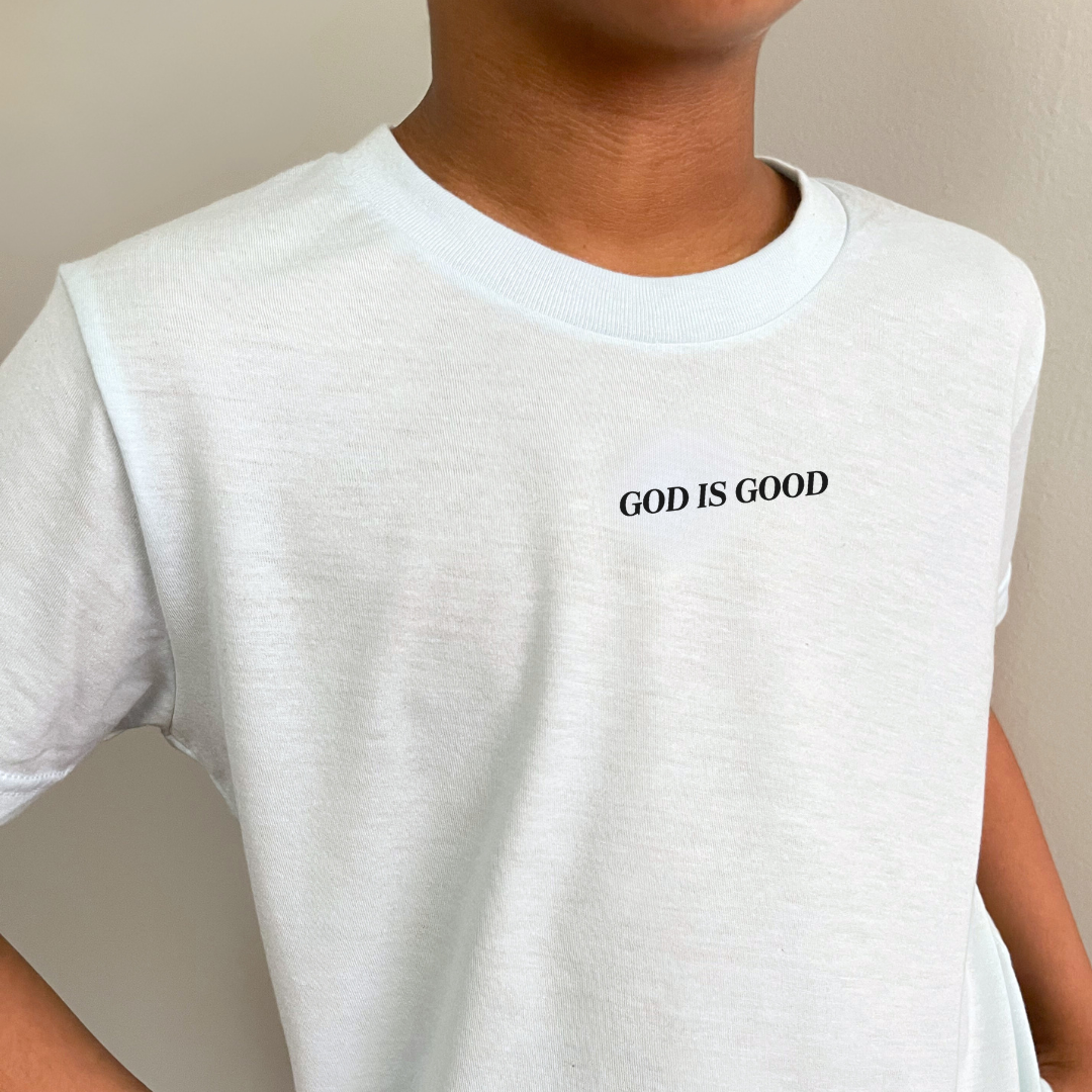 Young boy modeling the Kids graphic tee featuring the phrase “God Is Good” printed on the front from Branded & Labeled.