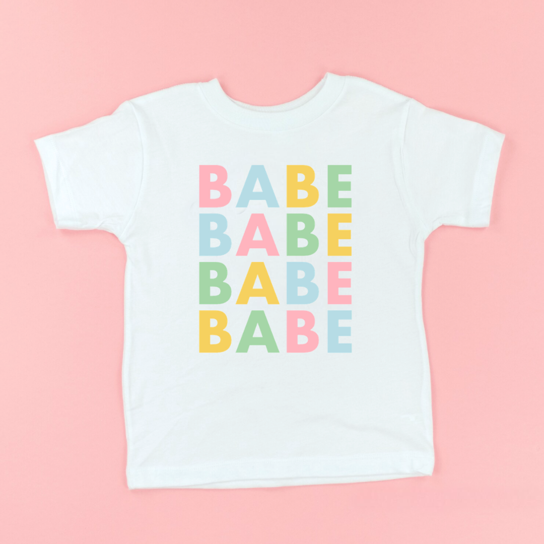 Kids natural colored graphic tee featuring the word “Babe” repeated four times in spring pastel colors printed on the front from the Branded & Labeled spring collection.