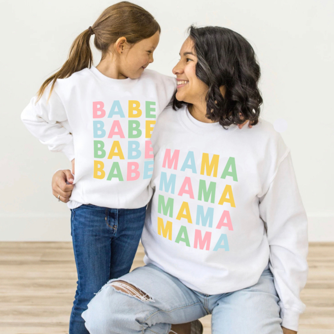 Mom and daughter wearing matching fleece pullovers with pastel “Mama” and “Babe” designs from the Branded & Labeled spring collection.