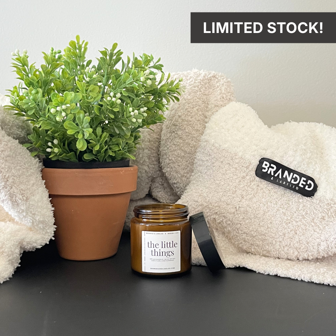 4oz Branded & Labeled soy candle displayed with a plant and a blanket, creating a warm and cozy lifestyle setting.
