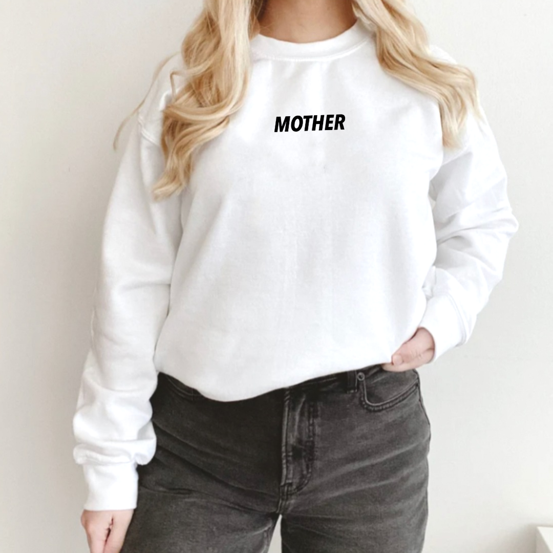 Woman modeling a white adult fleece pullover featuring subtle “MOTHER” text in a small all-caps font, printed at the center chest near the collar by Branded & Labeled