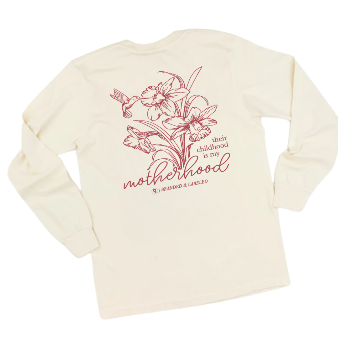 Flat lay image of the back of an adult premium long sleeve featuring “Their Childhood is My Motherhood” text with Branded & Labeled logo and name subtly printed underneath.