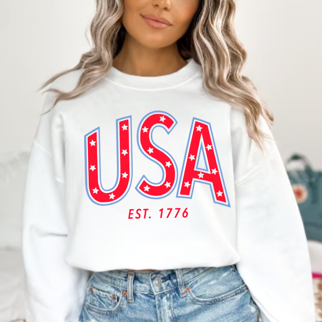 Adult fleece pullover featuring bold “USA” typography with est. 1776 detail in red and blue patriotic colors, part of the American Classics Collection by Branded & Labeled.