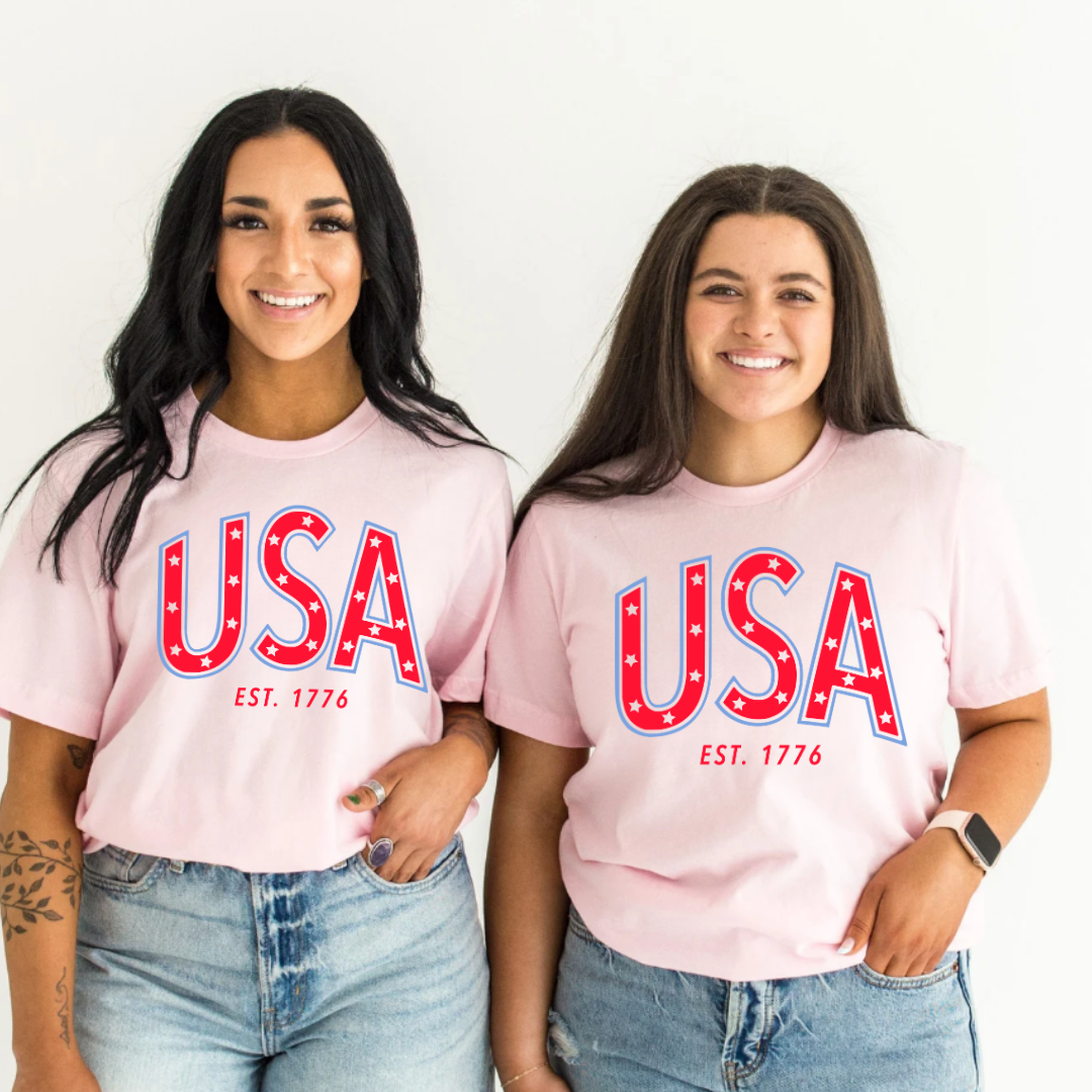 Adult everyday graphic tee featuring bold “USA” typography with est. 1776 detail in red and blue patriotic colors, part of the American Classics Collection by Branded & Labeled.