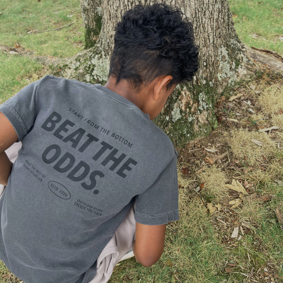 Young boy wearing the Branded & Labeled Beat the Odds premium youth heavyweight t-shirt from behind.