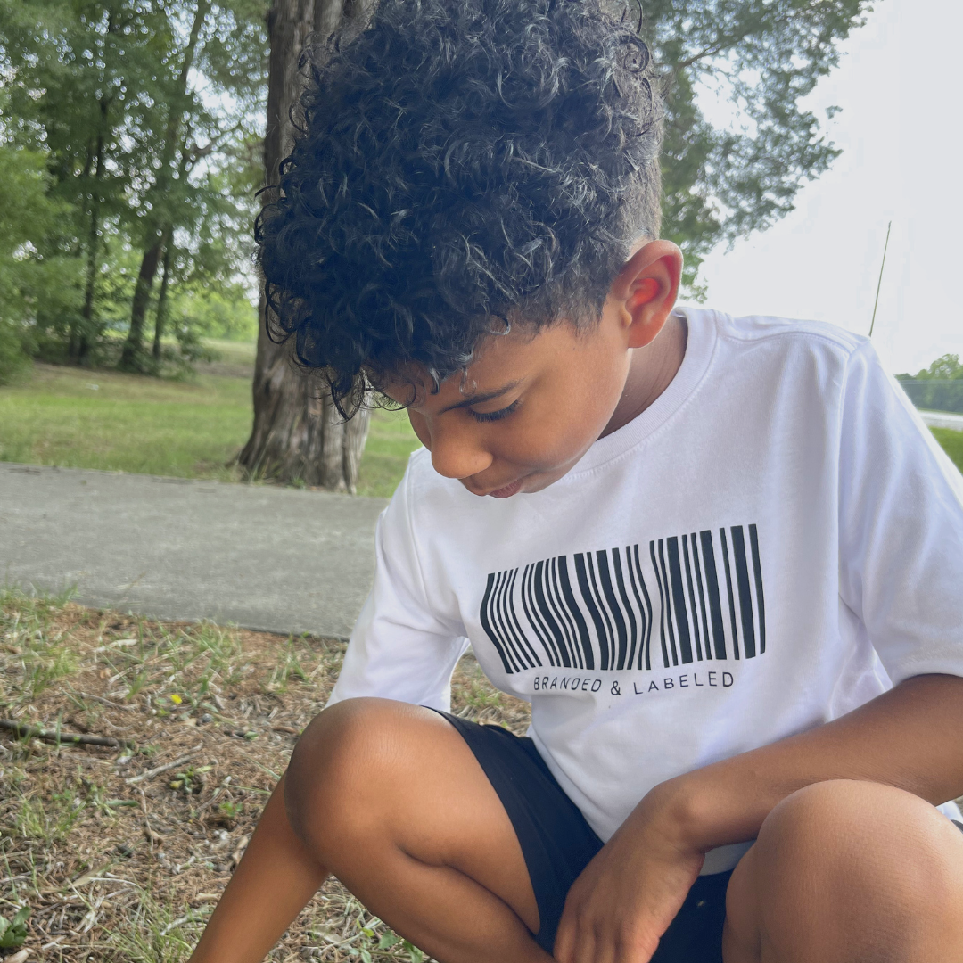 Young boy wearing The Identifier kids graphic tee featuring a barcode-inspired graphic with Branded & Labeled printed beneath on the front chest.