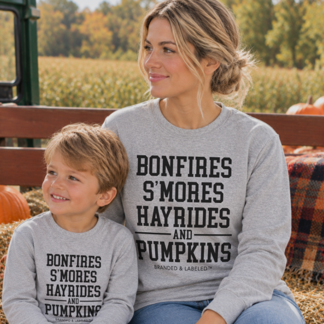 Mom and her son wearing matching Fall Traditions long sleeve shirts featuring bonfires, s’mores, hayrides and pumpkins.