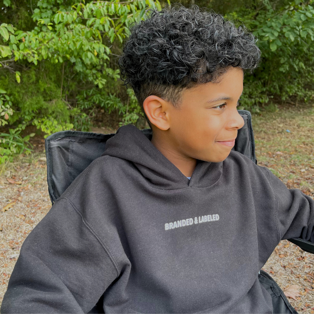 Kid wearing The Label Everyday Hooded Pullover, featuring subtle Branded & Labeled lettering in bold small caps near the front collar.